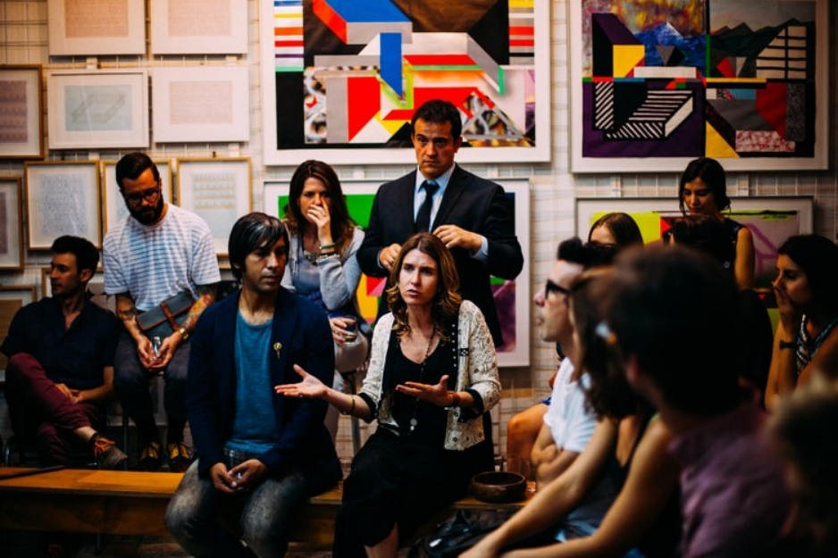 A group of people sitting around in front of some paintings.