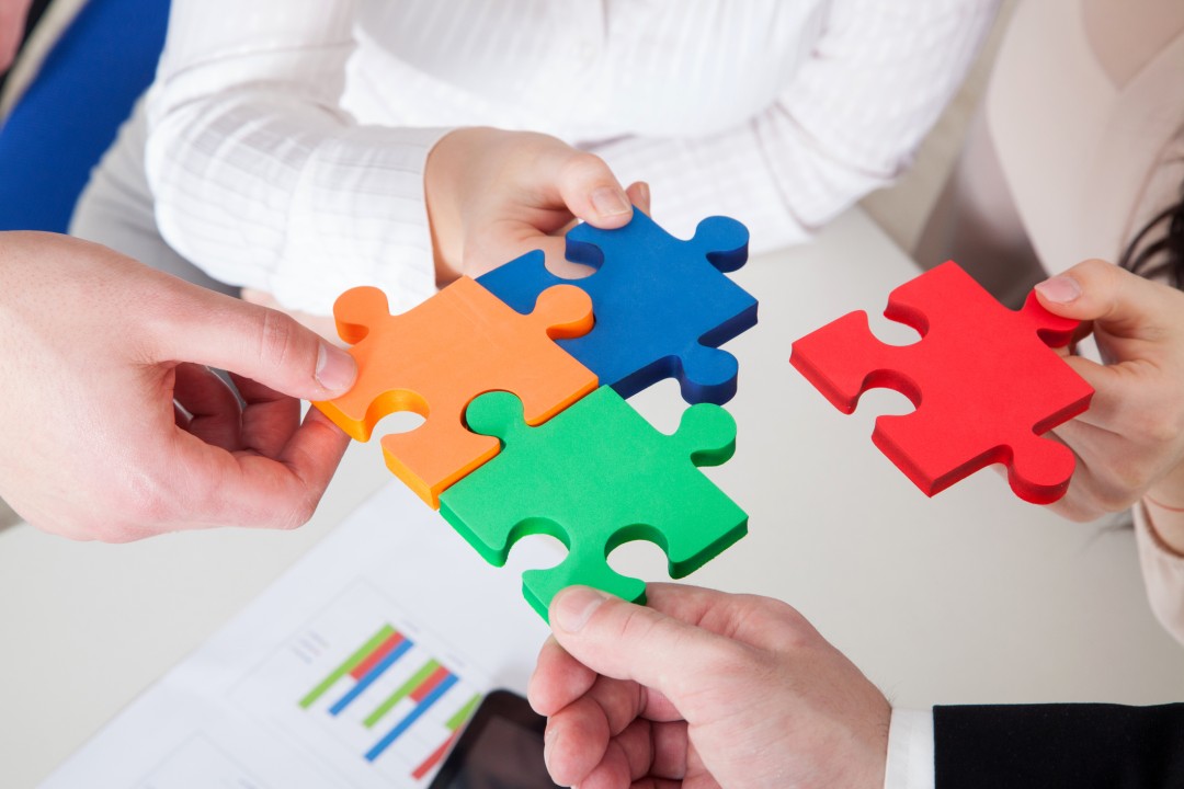 A group of people holding up puzzle pieces.