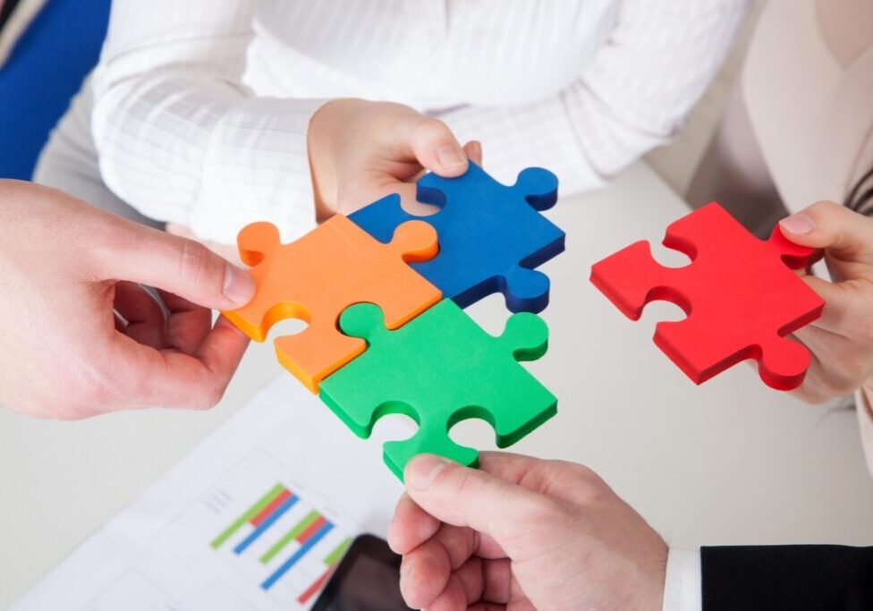 A group of people holding up puzzle pieces.